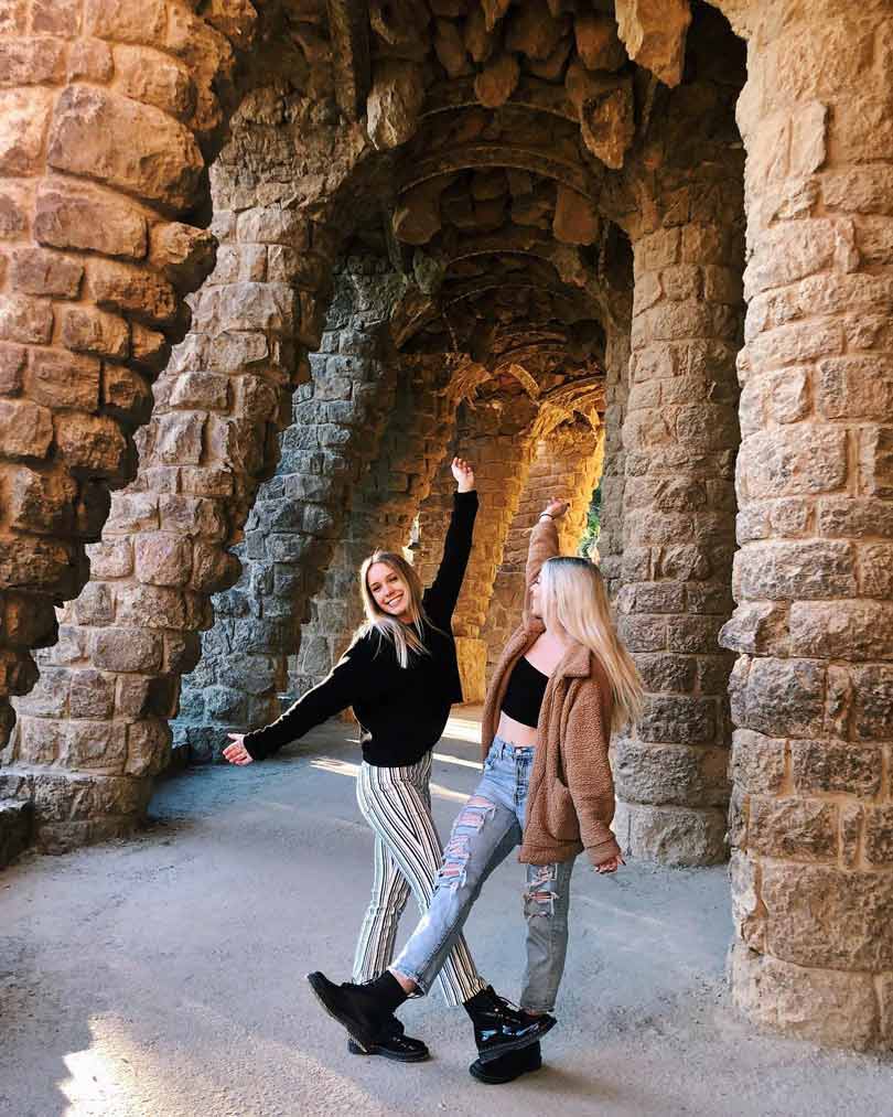 Two young woman in between the columns in colonnade of park guell